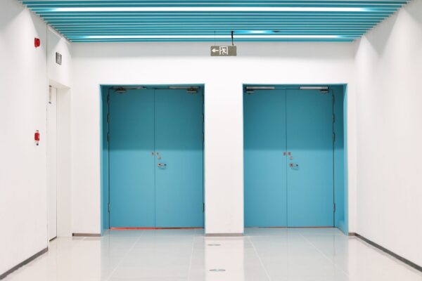 Two sets of teal double doors set against a white wall.